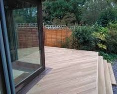 a wooden deck with glass doors leading to the back yard and trees in the background