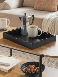 a coffee table with two cups on it and a tray that has some food in front of it