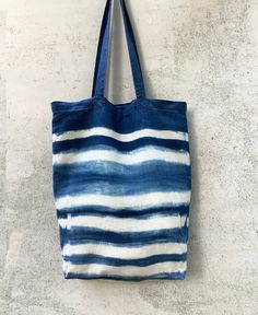 a blue and white tote bag hanging from a hook on a concrete wall or floor