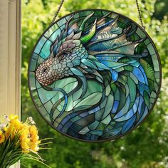 a stained glass window with a dragon head hanging from it's side and flowers in the foreground