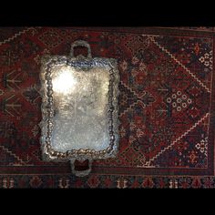 an antique mirror on top of a rug with a light shining in the middle,