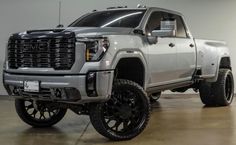 a silver truck parked in a garage next to a white wall and black rims