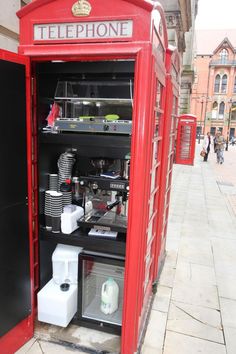 a red phone booth sitting on the side of a street