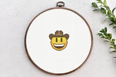 a cross stitch pattern with a smiley face wearing a cowboy hat