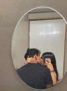 a man and woman taking a selfie in front of a mirror