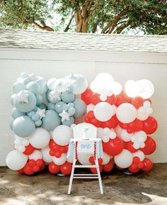 a chair sitting in front of a bunch of balloons