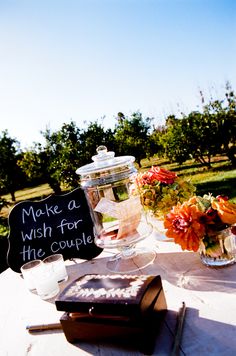 a table topped with books and vases filled with flowers next to a sign that says make a wish for his couple