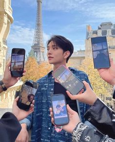 four people holding up their cell phones in front of the eiffel tower