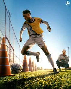 two men are playing soccer on the field with cones in front of them and an orange cone behind them