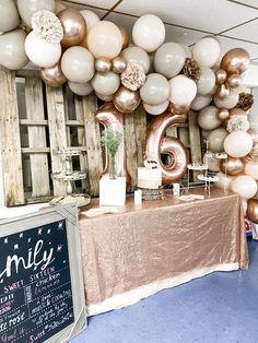 a table topped with lots of balloons next to a chalkboard sign that says 16