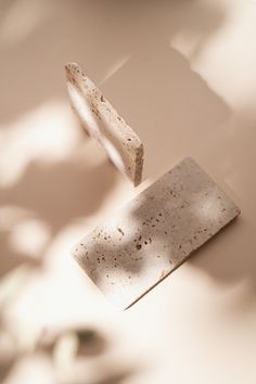 a piece of white marble sitting on top of a table next to a leafy plant