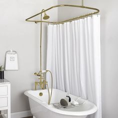 a white bath tub sitting next to a shower with black faucet and hand held shower head