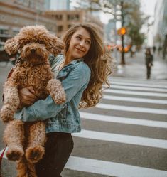 a woman holding a brown dog on the side of a road with traffic lights in the background