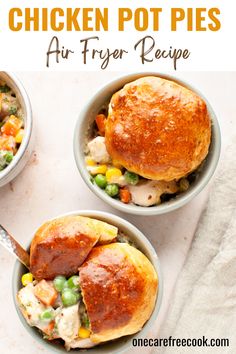 two bowls filled with chicken pot pies on top of a white table next to a fork