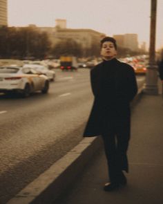 a man standing on the side of a road next to traffic