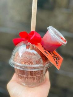 a person holding up a cup with some kind of drink in it and a red bow on the top