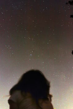 a woman standing in front of a night sky filled with stars