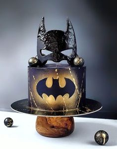 a batman themed cake on top of a wooden stand