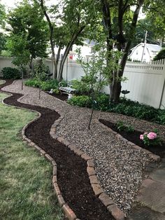 a garden area with gravel, rocks and trees