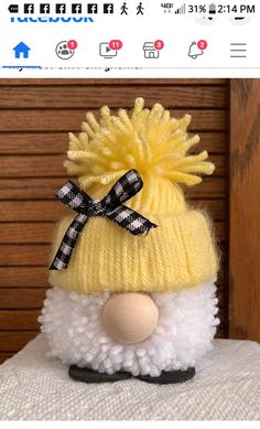 a stuffed animal with a yellow hat and black bow on it's head sitting on a pillow