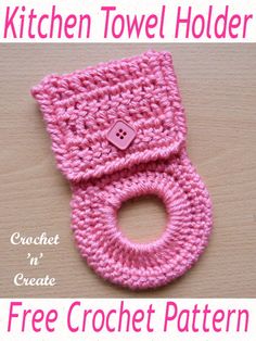 a pink crochet towel holder with a button on the front and bottom, sitting on top of a wooden table