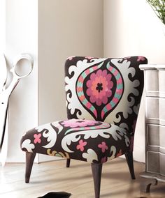 a white dresser sitting next to a black and pink chair