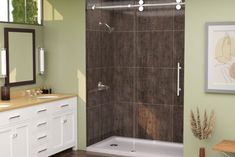 a bathroom with a walk in shower next to a white sink and wooden flooring