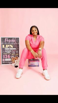 a woman sitting on top of a stack of books in front of a pink background