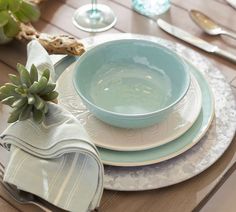 a table set with plates, napkins and succulents