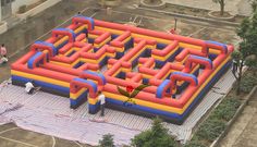 an inflatable maze is set up on the ground with people walking around it