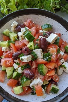 a bowl filled with cucumber, tomato and feta cheese on top of lettuce