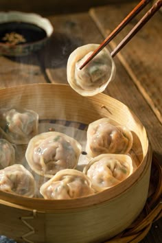 dumplings being cooked in a bamboo steamer with chopsticks sticking out of it