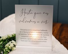 there is a card that has been placed on the table with flowers in front of it