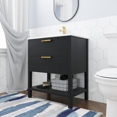 a white toilet sitting next to a black cabinet in a bathroom under a round mirror