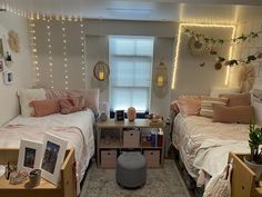 two twin beds in a dorm room with string lights on the wall and pictures hanging above them