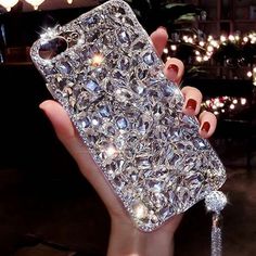 a woman holding up her phone case with diamonds on it