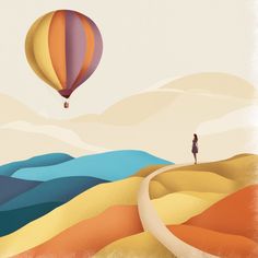 a person standing on top of a hill under a hot air balloon