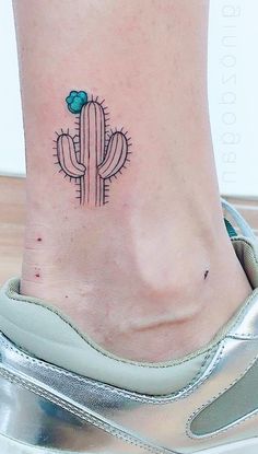 a small cactus tattoo on the side of a woman's foot with a blue flower