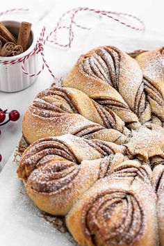 cinnamon star bread on a white plate with cinnamon sticks and cranberries in the background