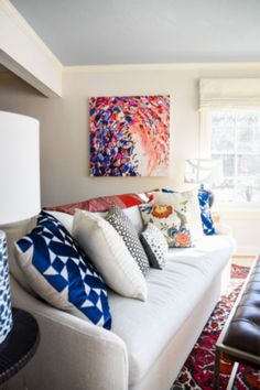 a living room filled with lots of furniture and pillows on top of a white couch