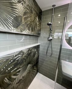 a bathroom with grey tile and palm leaves on the wall, along with a walk in shower