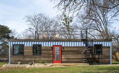 a house made out of shipping containers with a red door and stairs leading up to it