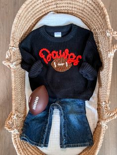 a football and jeans outfit sitting on top of a wicker basket