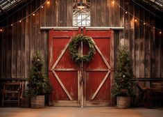 an open barn door with christmas wreaths on the front and side, surrounded by lights