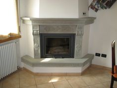 a fireplace in the corner of a room with tile flooring and a white mantle