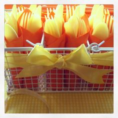 a basket filled with orange and yellow plastic utensils