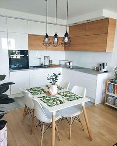 a kitchen with white cabinets and wooden flooring next to a dining table in front of an oven