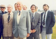 a group of men standing next to each other in suits and ties on a field