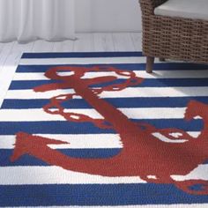 a red anchor on blue and white striped rug in front of a wicker chair