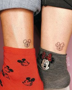 two people with matching mickey and minnie mouse tattoos on their legs, both wearing socks